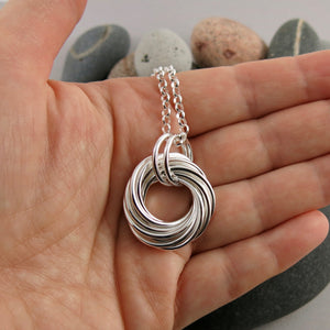 Boundless Love Knot Necklace: artisan made sterling silver infinite knot necklace displayed on a hand by Mikel Grant Jewellery