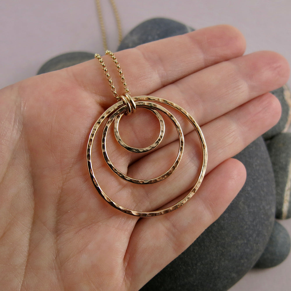 Nesting circles trio necklace in 14K gold fill by Mikel Grant Jewellery. Hammer textured open circles necklace.  Shown displayed on a hand.