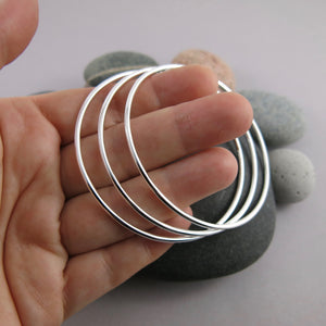 Artisan made thick smooth sterling silver bangle by Mikel Grant Jewellery.  Displayed on a hand.
