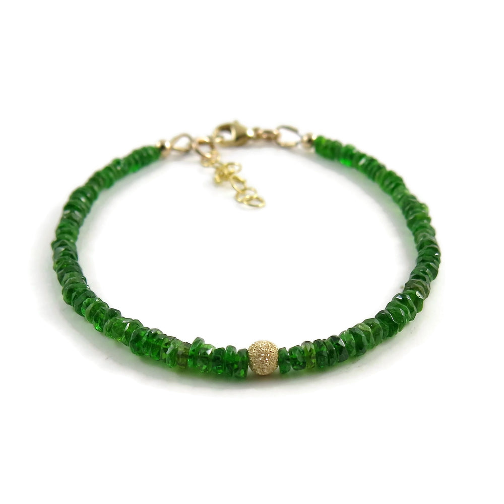 A bright green gemstone bead bracelet is displayed on a white background.  The chrome diopside beads are faceted and sparkly and the bracelet features a gold filled sparkly bead in the centre as well as gold filled clasp, ring and adjustable chain.