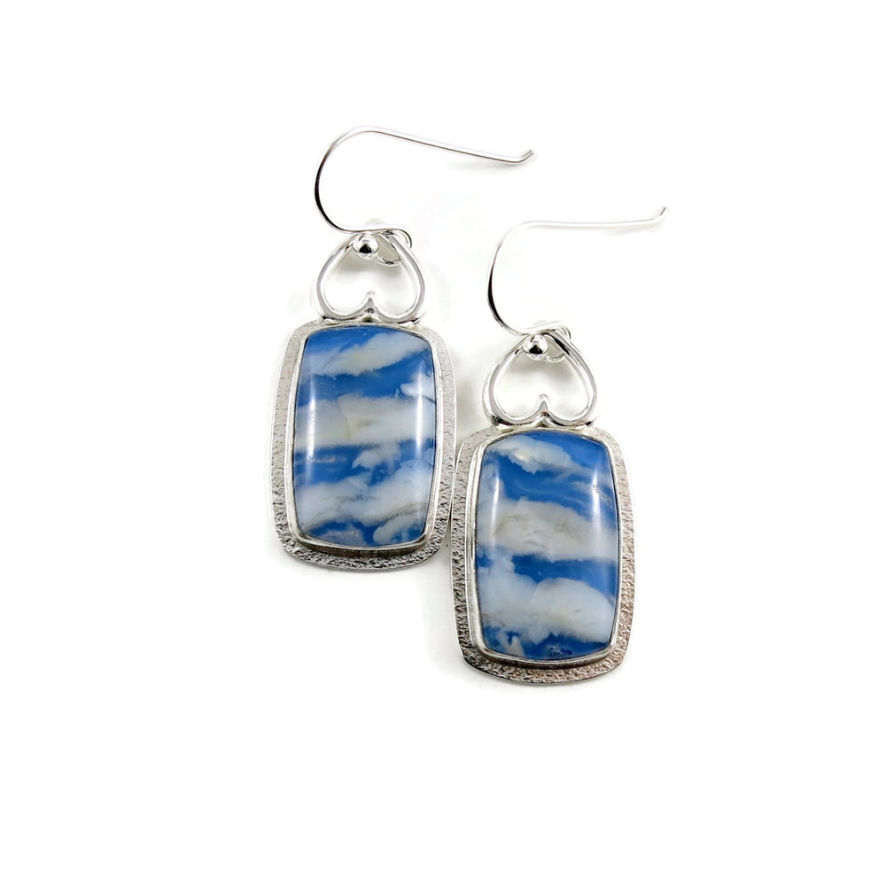 Daydream Earrings II by Mikel Grant Jewellery.  Rectangular plume agate doublets set in a sterling silver setting with upside down hearts at the top.  The plume agate doublets feature fluffy white clouds drifting across a vibrant blue sky. 