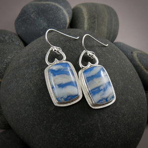 Daydream Earrings II by Mikel Grant Jewellery.  Rectangular plume agate doublets set in a sterling silver setting with upside down hearts at the top.  The plume agate doublets feature fluffy white clouds drifting across a vibrant blue sky. 