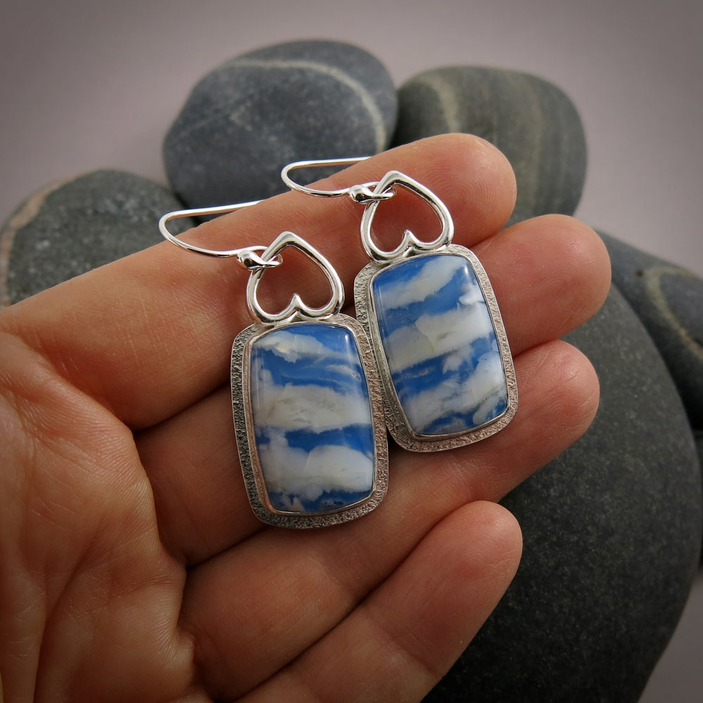 Daydream Earrings II by Mikel Grant Jewellery.  Rectangular plume agate doublets set in a sterling silver setting with upside down hearts at the top.  The plume agate doublets feature fluffy white clouds drifting across a vibrant blue sky. 