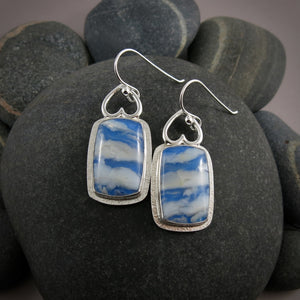 Daydream Earrings II by Mikel Grant Jewellery.  Rectangular plume agate doublets set in a sterling silver setting with upside down hearts at the top.  The plume agate doublets feature fluffy white clouds drifting across a vibrant blue sky. 