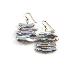 A pair of grey pearl earrings are displayed on a white background.  The earrings feature a stack of five organically shaped keshi toothpick earrings on a gold headpin with gold ear wires.