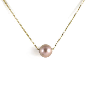 A pearl necklace is displayed on a white background.  The round, lilac-pink pearl is suspended on a yellow gold filled rolo chain that slides through the centre of the pearl.