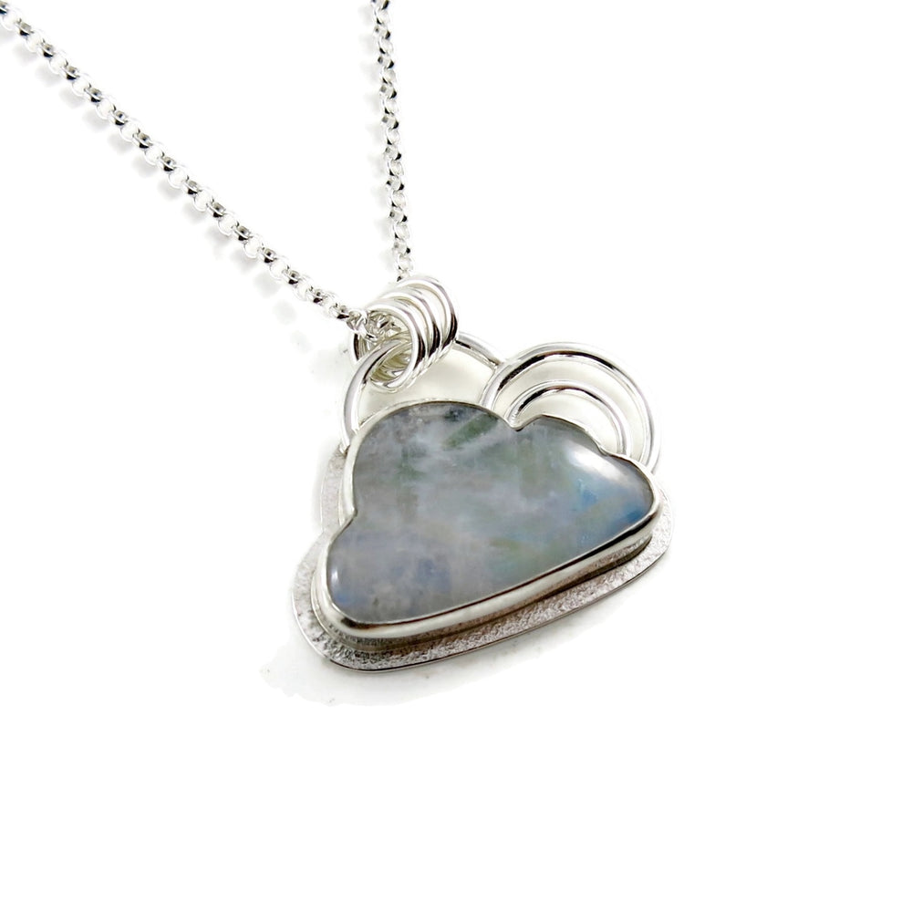 A sterling silver necklace featuring a cloud shaped rainbow moonstone.  The cloud is bezel set and has a silver "lining" around the outside and two silver curved pieces above the cloud resembling a rainbow.  