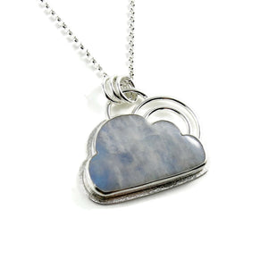 A handcrafted sterling silver necklace by Mikel Grant Jewellery.  A rainbow moonstone shaped like a cloud is set in sterling silver with a "silver lining" of silver surrounding the gem.  A double "rainbow" of curved silver wire rests atop the cloud.