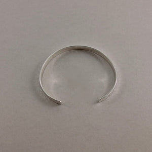 Narrow convex cuff bracelet in hammer textured sterling silver by Mikel Grant Jewellery