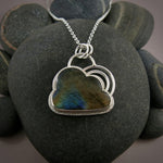 Silver linings necklace by Mikel Grant Jewellery.  An electric blue and orange labradorite gemstone carved into the shape of a cloud is set in a sterling silver setting with a silver "lining" around the piece and a double silver "rainbow" sits above the cloud.  