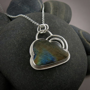 Silver linings necklace by Mikel Grant Jewellery.  An electric blue and orange labradorite gemstone carved into the shape of a cloud is set in a sterling silver setting with a silver "lining" around the piece and a double silver "rainbow" sits above the cloud.  