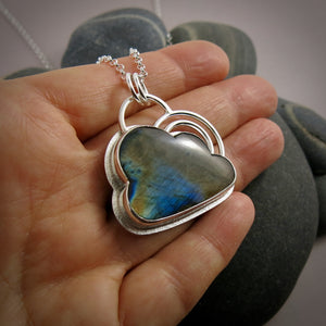 Silver linings necklace by Mikel Grant Jewellery.  An electric blue and orange labradorite gemstone carved into the shape of a cloud is set in a sterling silver setting with a silver "lining" around the piece and a double silver "rainbow" sits above the cloud.  