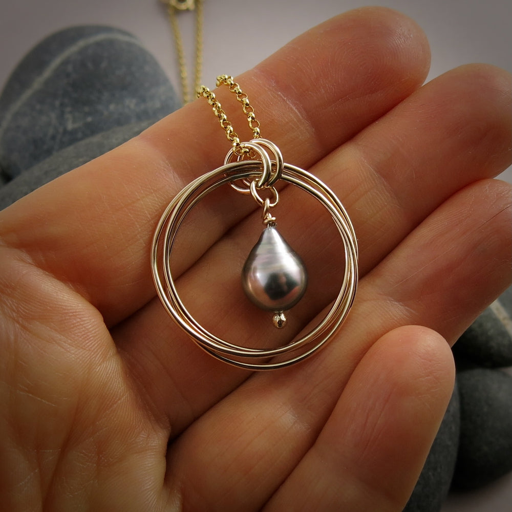 10K Gold Knot Pendant with a Silver Tahitian Pearl Drop in the Centre.  Displayed on a hand.