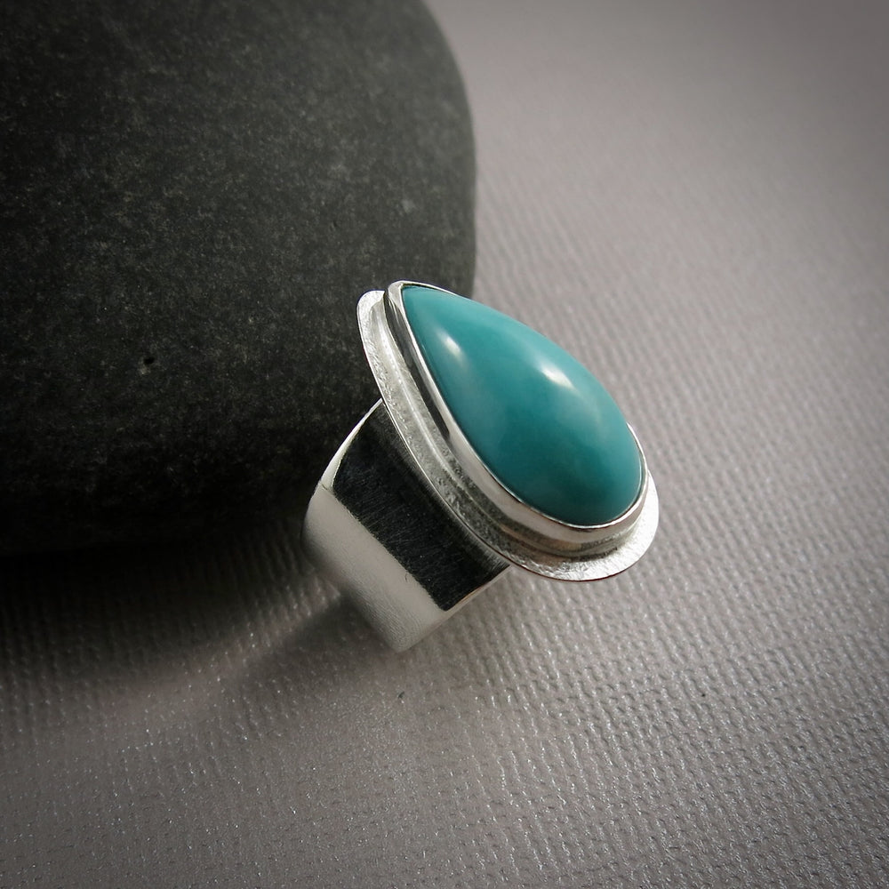 Turquoise talon on a wide silver saddle ring band by Mikel Grant Jewellery.  Size 7.5
