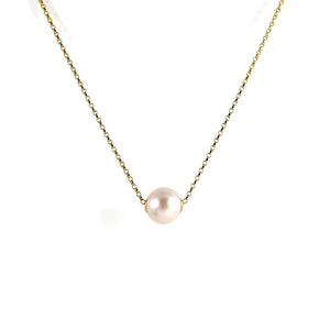 A single pearl necklace on a gold chain is displayed on a white background.  The round white pearl can slide back and forth on the flat gold rolo chain that goes through the middle of the pearl.