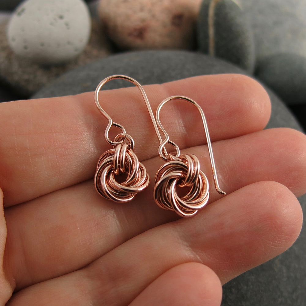 Algerian love knot earrings in 14K rose gold fill by Mikel Grant Jewellery. Artisan made.  Displayed on a hand.