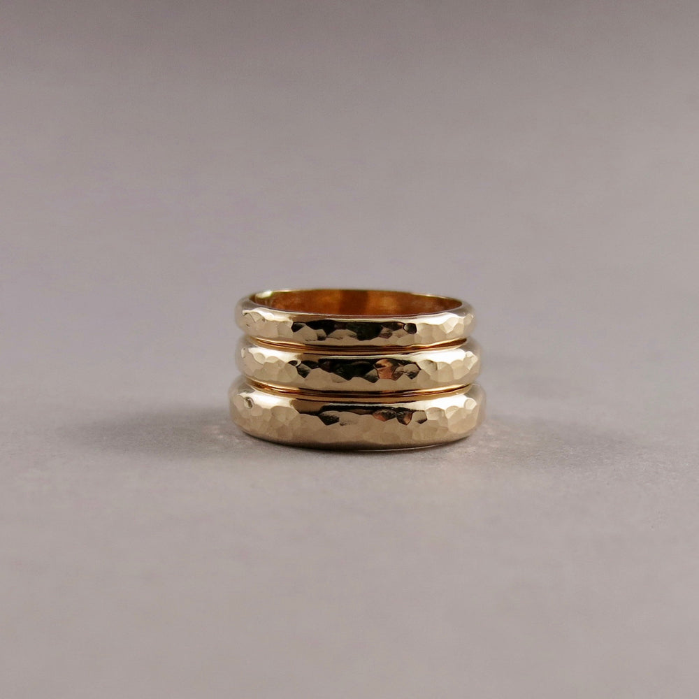 Stack of 14K gold steadfast rings in narrow, medium and wide widths by Mikel Grant Jewellery.