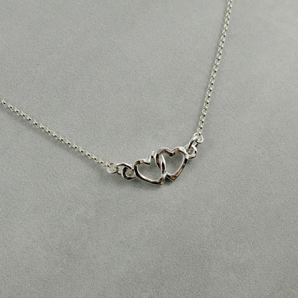Hearts embrace necklace in sterling silver by Mikel Grant Jewellery.