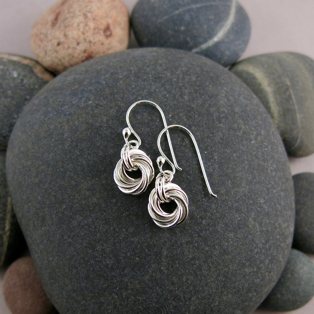 Love knot earrings in sterling silver by Mikel Grant Jewellery.  Displayed on a beach rock.