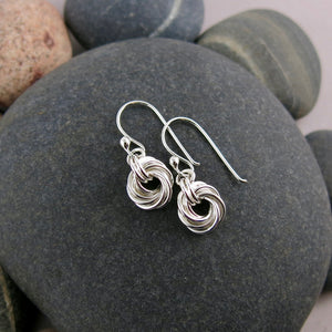 Love knot earrings in sterling silver by Mikel Grant Jewellery. Displayed on a beach rock.