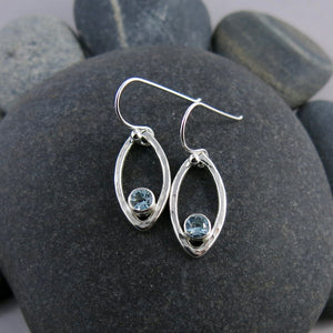 Minimalist sterling silver leaf earrings with faceted blue topaz gemstones by Mikel Grant Jewellery.