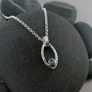 Modern minimalist sterling silver leaf necklace with faceted blue topaz gemstone by Mikel Grant Jewellery.