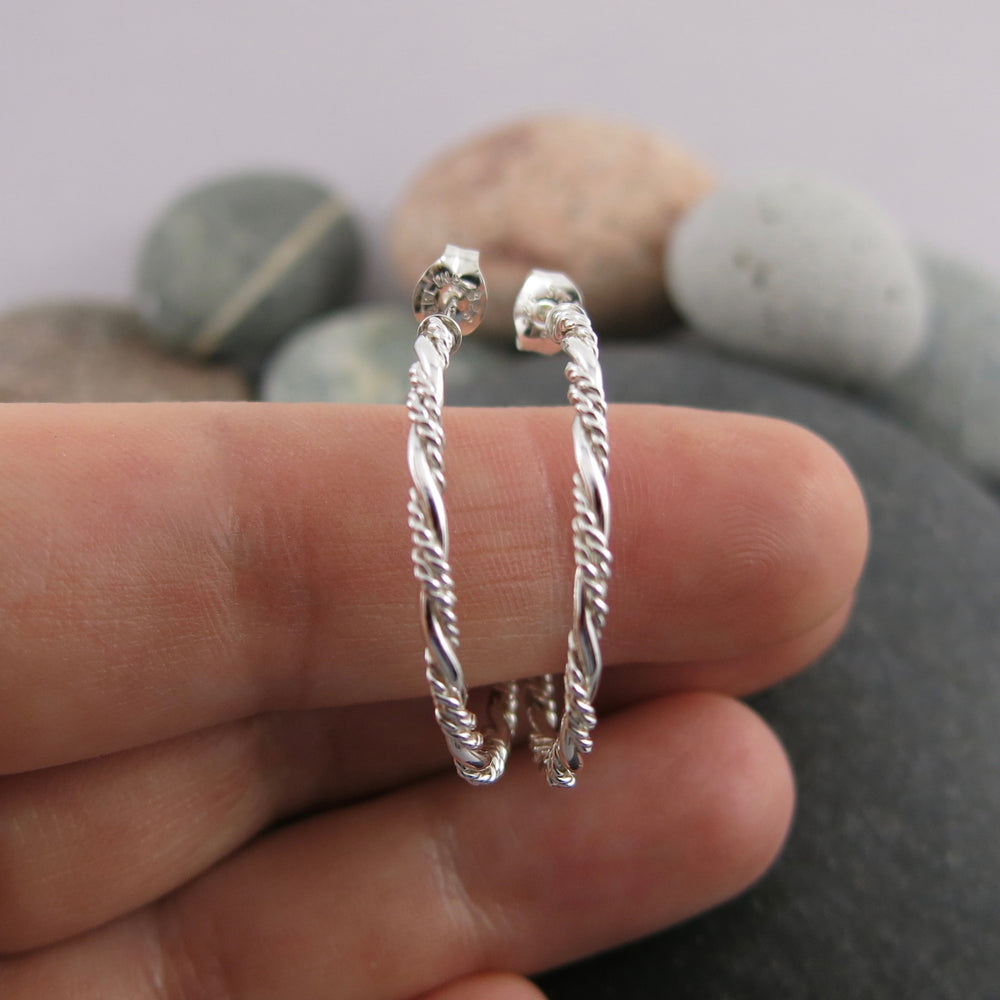 Sterling silver ornate twist open hoop stud earrings displayed on a hand by Mikel Grant Jewellery. Artisan made on the Sunshine Coast of BC.