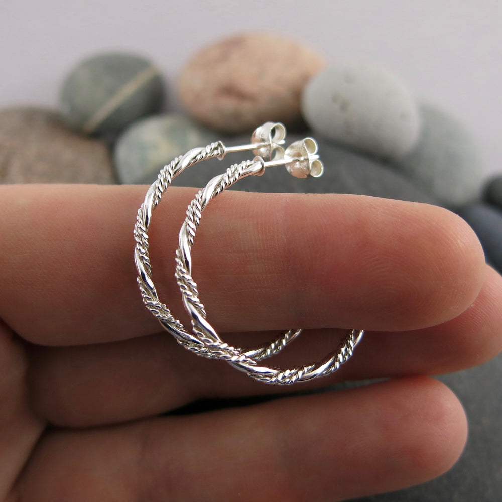 Sterling silver ornate twist open hoop stud earrings displayed on a hand by Mikel Grant Jewellery. Artisan made on the Sunshine Coast of BC.